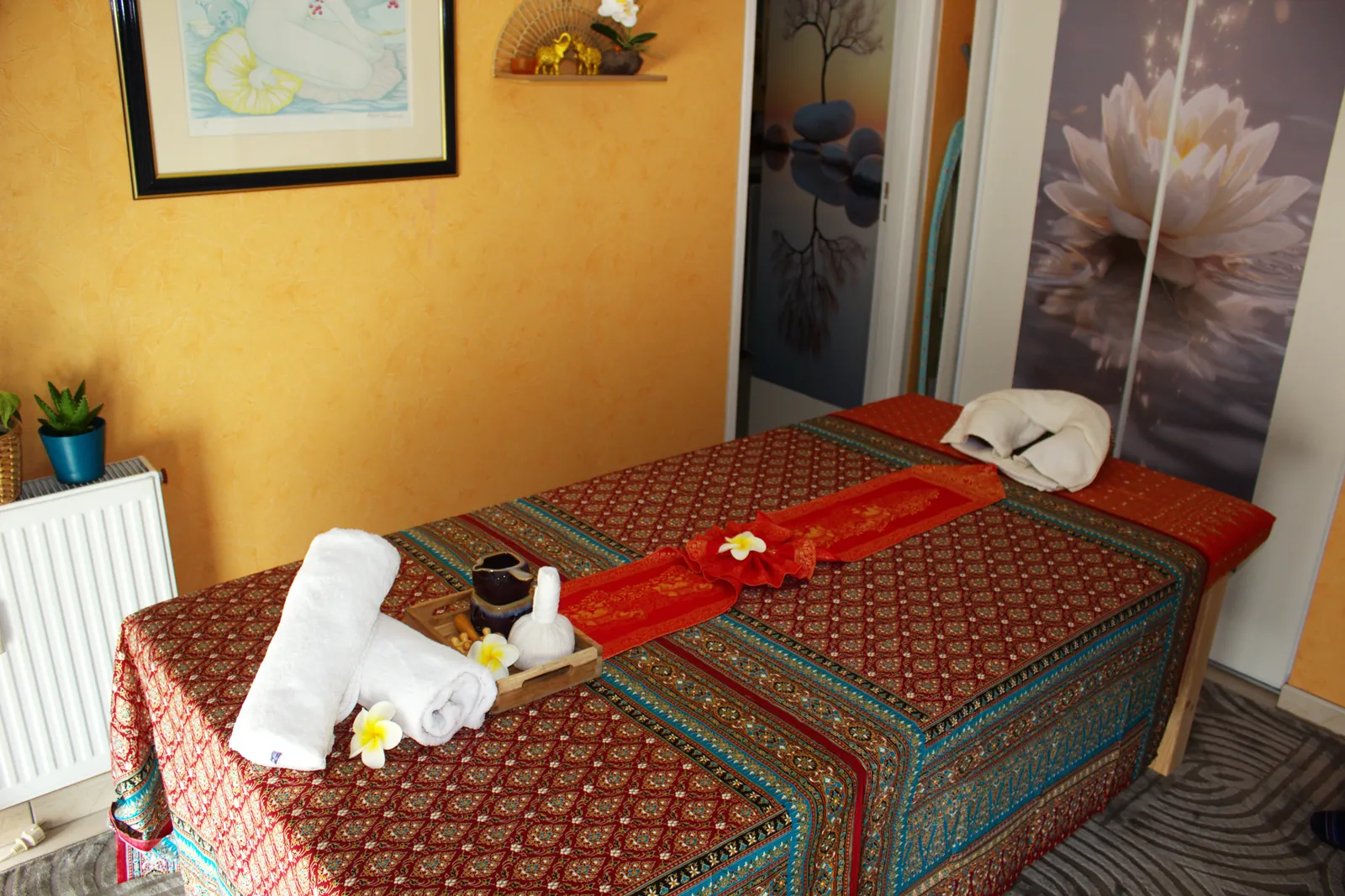 Table de massage thaïlandais chez Fay Thaï à Metz, dressée avec tissu traditionnel, serviettes et fleur de lotus